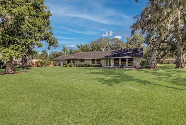 332 N Amherst Dr, West Columbia, TX 77486 - back of property with a chimney, a lawn, and french doors