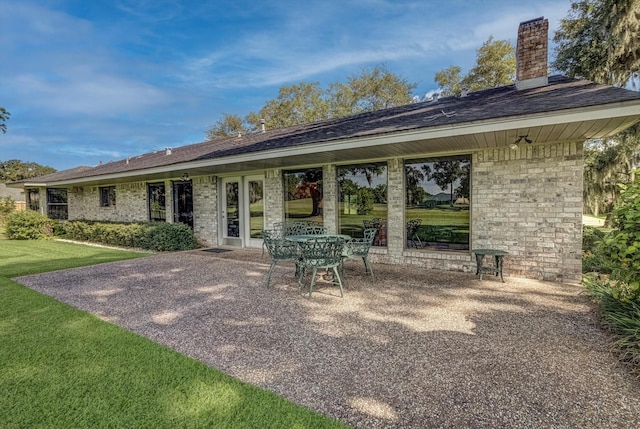 332 N Amherst Dr, West Columbia, TX 77486 - back of house featuring a patio area, a chimney, brick siding, a lawn, and a shingled roof