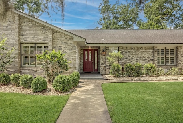 332 N Amherst Dr, West Columbia, TX 77486 - view of exterior entry with a yard, brick siding, and roof with shingles