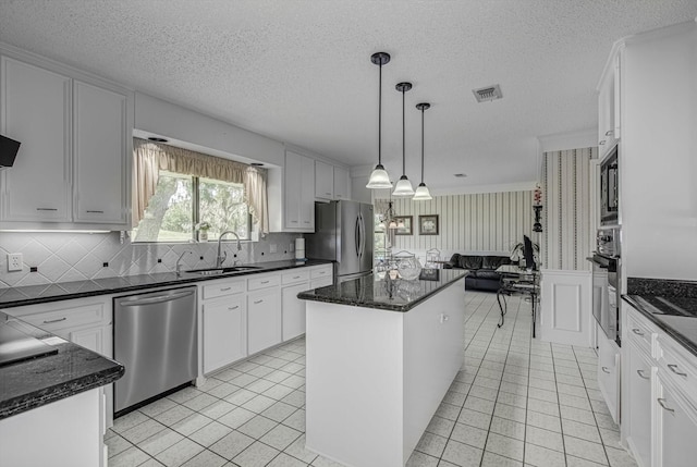 332 N Amherst Dr, West Columbia, TX 77486 - kitchen with stainless steel appliances, a center island, white cabinetry, a wainscoted wall, and a textured ceiling