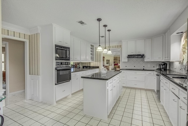332 N Amherst Dr, West Columbia, TX 77486 - kitchen featuring black appliances, a kitchen island, under cabinet range hood, white cabinets, and backsplash