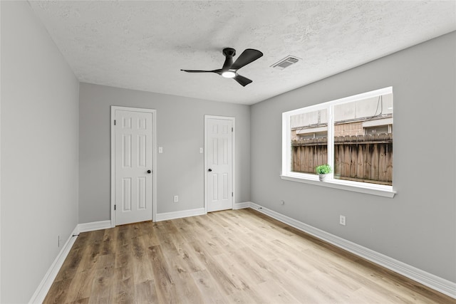 10503 Long River Dr, Sugar Land, TX 77498 - unfurnished bedroom with wood finished floors, a textured ceiling, a ceiling fan, and two closets