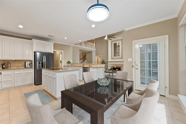 1922 Briarchester Dr, Katy, TX 77450 - dining room featuring light tile patterned floors, ceiling fan, ornamental molding, a lit fireplace, and recessed lighting