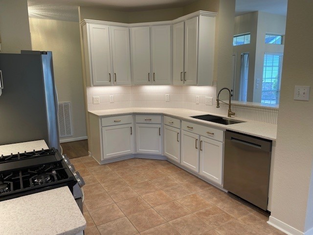 2111 Ridge Wood Ln, Sugar Land, TX 77479 - kitchen featuring stainless steel appliances, light countertops, white cabinets, and decorative backsplash