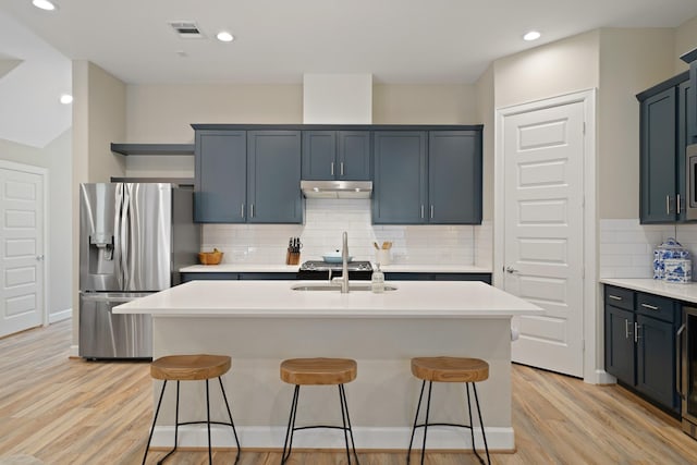911 W 35th St Unit C, Houston, TX 77018 - kitchen with stainless steel refrigerator with ice dispenser, under cabinet range hood, light wood-style floors, a breakfast bar area, and backsplash