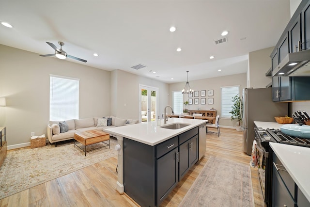 911 W 35th St Unit C, Houston, TX 77018 - kitchen featuring stainless steel range with gas cooktop, light countertops, open floor plan, a center island with sink, and light wood-style floors