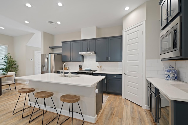 911 W 35th St Unit C, Houston, TX 77018 - kitchen featuring stainless steel appliances, a breakfast bar area, under cabinet range hood, light wood-style flooring, and recessed lighting