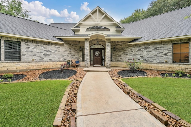 11304 Monarchs Way, Montgomery, TX 77316 - view of exterior entry featuring roof with shingles, a yard, and brick siding