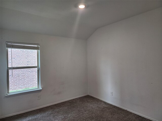 20390 Tembec Dr, New Caney, TX 77357 - empty room with vaulted ceiling, healthy amount of natural light, and dark carpet