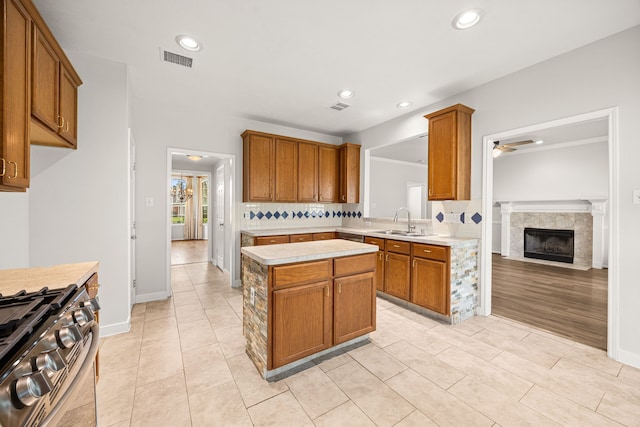 2722 Round Hill Ct, Katy, TX 77494 - kitchen featuring stainless steel gas stove, light countertops, ceiling fan, a kitchen island, and decorative backsplash