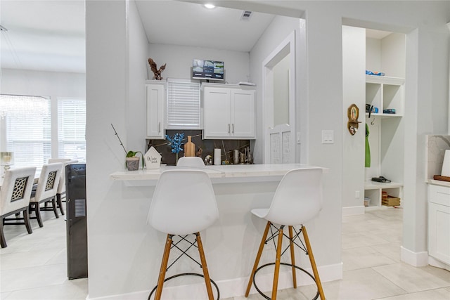 4821 1st St, Houston, TX 77504 - kitchen featuring a breakfast bar area, white cabinets, built in shelves, light countertops, and light tile patterned floors