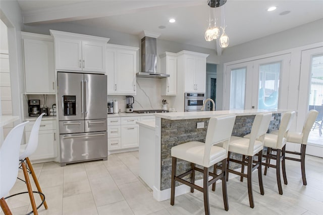 4821 1st St, Houston, TX 77504 - kitchen with stainless steel appliances, wall chimney range hood, a breakfast bar, white cabinetry, and recessed lighting