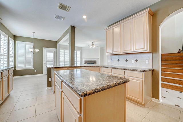13212 Lismore Pt, Cypress, TX 77429 - kitchen with a peninsula, light tile patterned floors, a ceiling fan, a kitchen island, and healthy amount of natural light