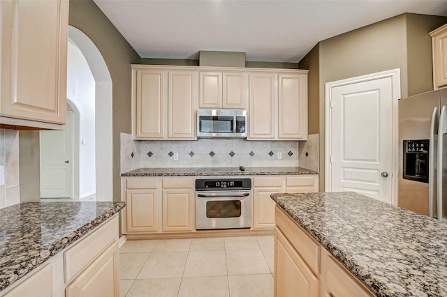 13212 Lismore Pt, Cypress, TX 77429 - kitchen with stainless steel appliances, arched walkways, dark stone countertops, and backsplash