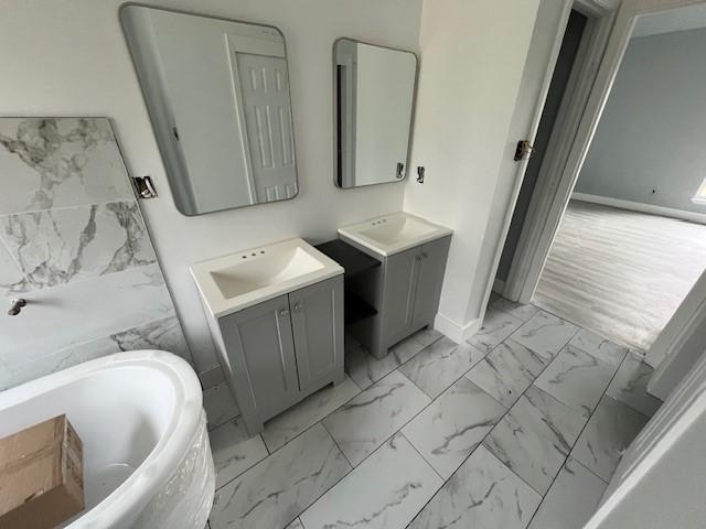 6985 Ellen Ln, Beaumont, TX 77708 - bathroom featuring marble look tiles, a tub, and two vanities