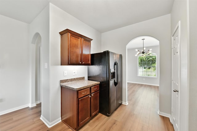 737 Grassy Knoll Ln, La Marque, TX 77568 - kitchen featuring black fridge with ice dispenser, arched walkways, light wood-style floors, and a chandelier