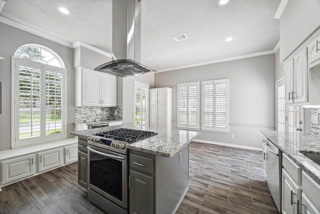 15814 Hillside Falls Trl, Houston, TX 77062 - kitchen with appliances with stainless steel finishes, island exhaust hood, a textured ceiling, ornamental molding, and light stone counters