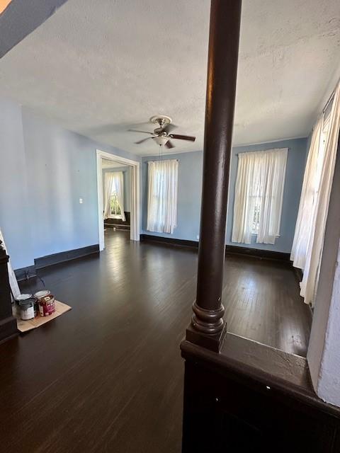 915 11th St, Galveston, TX 77550 - unfurnished living room with ceiling fan, a textured ceiling, wood finished floors, and a wood stove