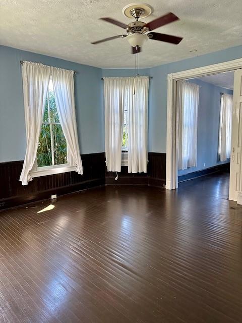 915 11th St, Galveston, TX 77550 - empty room featuring a ceiling fan, wood finished floors, wainscoting, and a textured ceiling