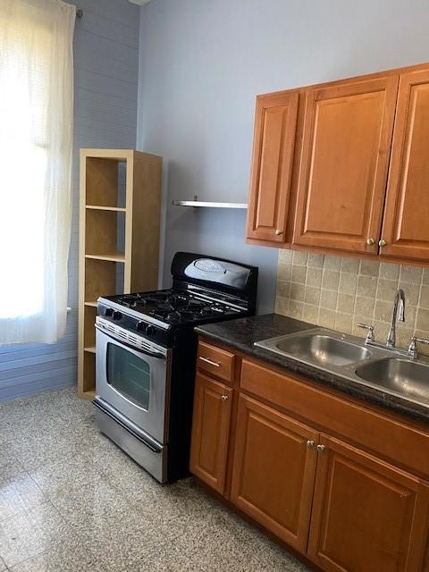 915 11th St, Galveston, TX 77550 - kitchen featuring gas stove, brown cabinets, dark countertops, backsplash, and open shelves