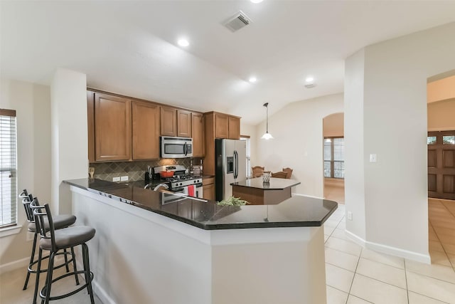 11410 Sandstone Canyon Dr, Humble, TX 77396 - kitchen with appliances with stainless steel finishes, dark countertops, arched walkways, healthy amount of natural light, and vaulted ceiling