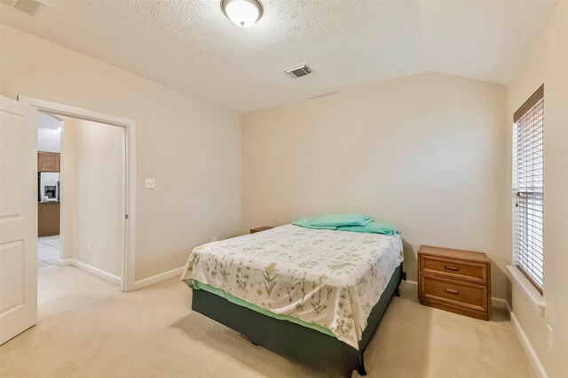 11410 Sandstone Canyon Dr, Humble, TX 77396 - bedroom with light colored carpet, refrigerator with ice dispenser, lofted ceiling, and a textured ceiling