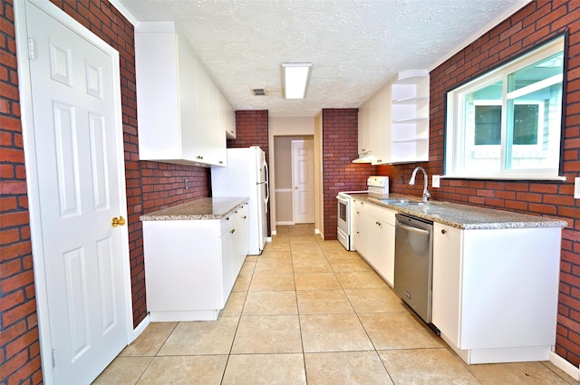 7354 Stone Pine Ln, Houston, TX 77041 - kitchen with white appliances, brick wall, a textured ceiling, white cabinetry, and light tile patterned flooring