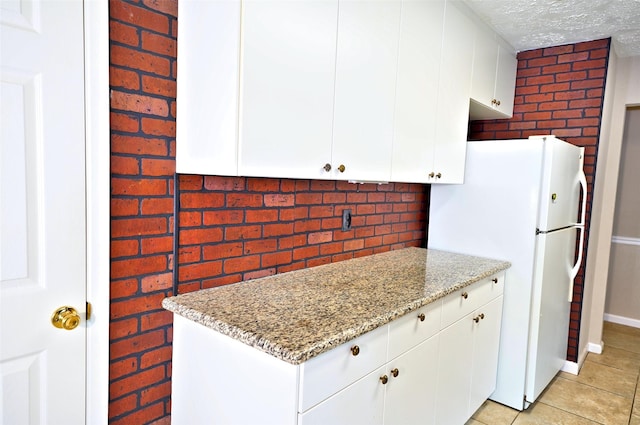 7354 Stone Pine Ln, Houston, TX 77041 - kitchen featuring freestanding refrigerator, light stone counters, white cabinets, a textured ceiling, and light tile patterned flooring