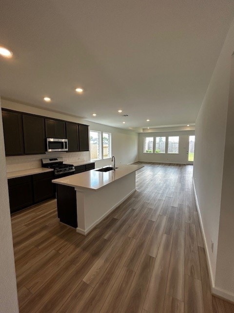 1123 Buffalo Run, Tomball, TX 77375 - kitchen featuring stainless steel microwave, gas range oven, recessed lighting, open floor plan, and wood finished floors