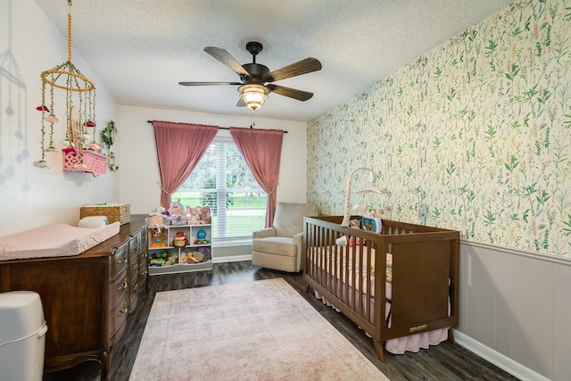 105 Pleasant Valley Dr, West Columbia, TX 77486 - bedroom with wallpapered walls, wood finished floors, a nursery area, wainscoting, and a textured ceiling