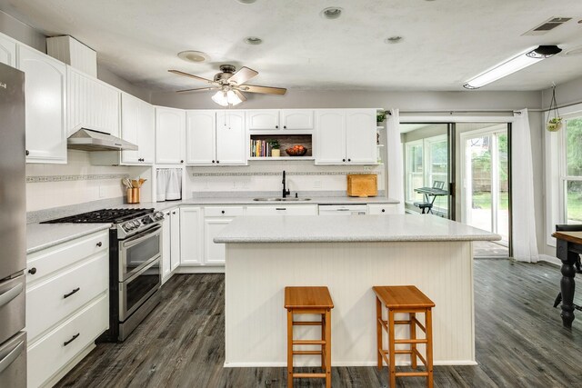 105 Pleasant Valley Dr, West Columbia, TX 77486 - kitchen with range with two ovens, range hood, a kitchen bar, open shelves, and decorative backsplash