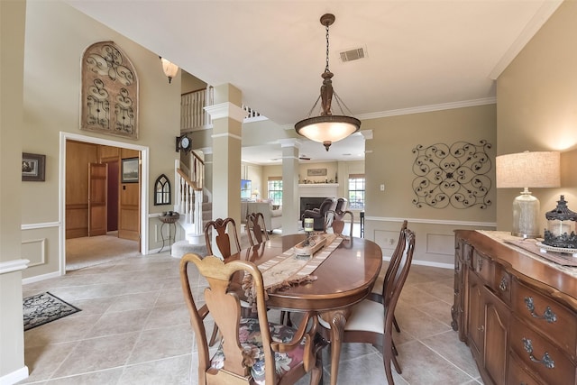 16219 Rainbow Lake Rd, Houston, TX 77095 - dining room featuring decorative columns, a decorative wall, light tile patterned floors, stairs, and crown molding