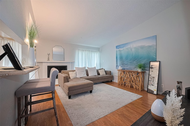 700 Thicket Ln Unit 306, Houston, TX 77079 - living room with wood finished floors, lofted ceiling, a tile fireplace, and a textured ceiling