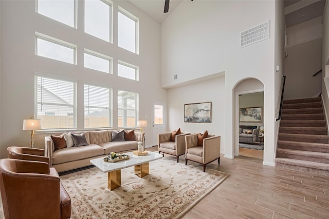 10023 Rose Mallow Ln, Magnolia, TX 77354 - living room featuring stairway, a high ceiling, arched walkways, light wood-style flooring, and ceiling fan