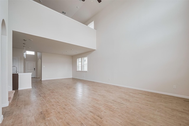 10023 Rose Mallow Ln, Magnolia, TX 77354 - unfurnished living room with ceiling fan, arched walkways, light wood-style flooring, and a high ceiling