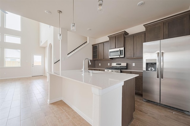 10023 Rose Mallow Ln, Magnolia, TX 77354 - kitchen featuring stainless steel appliances, dark brown cabinets, tasteful backsplash, light countertops, and a center island with sink