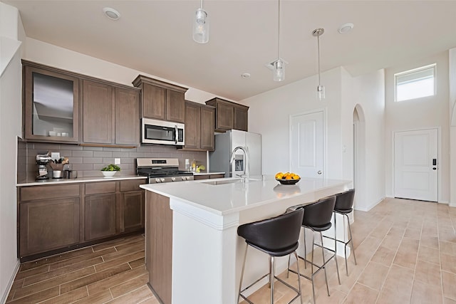 10023 Rose Mallow Ln, Magnolia, TX 77354 - kitchen with appliances with stainless steel finishes, arched walkways, wood finish floors, tasteful backsplash, and an island with sink