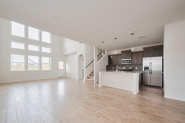 10023 Rose Mallow Ln, Magnolia, TX 77354 - kitchen with appliances with stainless steel finishes, open floor plan, arched walkways, light countertops, and a high ceiling