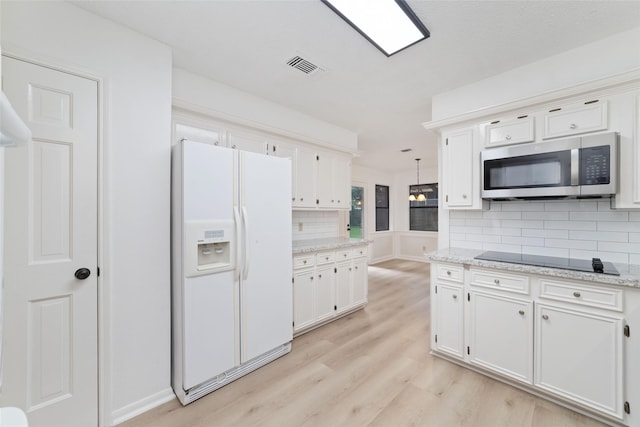 18307 Cransley Dr, Houston, TX 77084 - kitchen with white refrigerator with ice dispenser, stainless steel microwave, black electric cooktop, light wood-type flooring, and backsplash