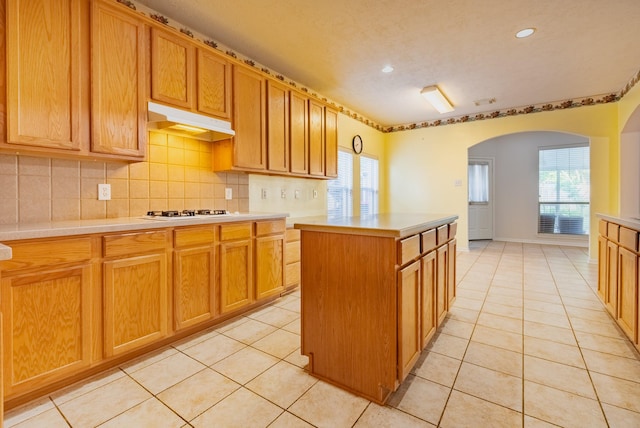 7907 Swan Hollow Ct, Houston, TX 77041 - kitchen featuring under cabinet range hood, arched walkways, light tile patterned floors, light countertops, and recessed lighting
