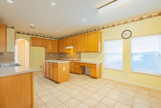 7907 Swan Hollow Ct, Houston, TX 77041 - kitchen with under cabinet range hood, backsplash, light countertops, arched walkways, and white gas cooktop