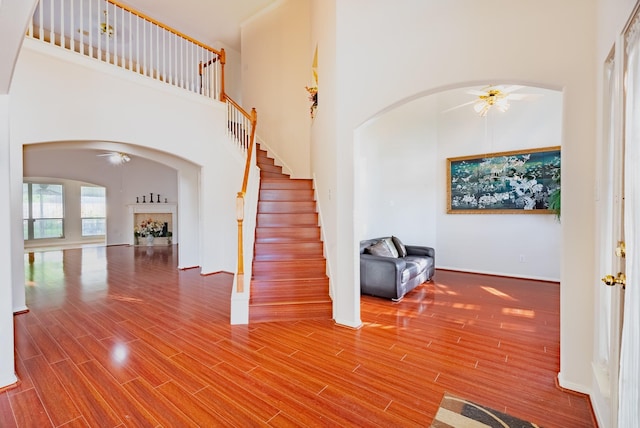 7907 Swan Hollow Ct, Houston, TX 77041 - staircase with arched walkways, ceiling fan, a towering ceiling, a fireplace, and wood finished floors