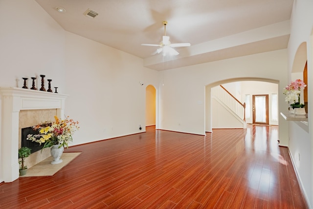 7907 Swan Hollow Ct, Houston, TX 77041 - unfurnished living room featuring arched walkways, a ceiling fan, wood finished floors, a tiled fireplace, and stairway