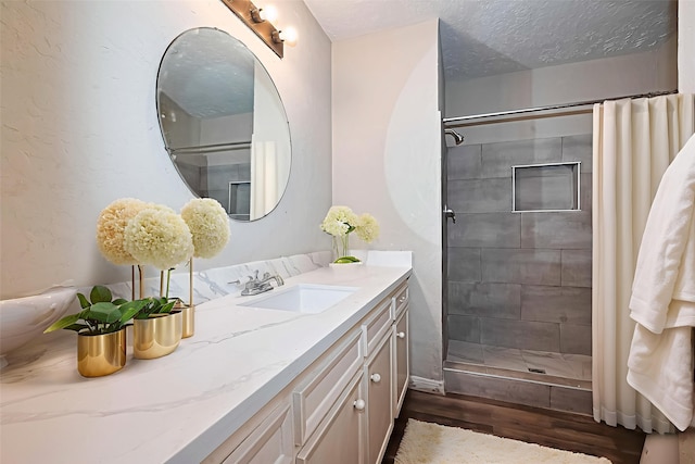 4307 Jura Dr, Houston, TX 77084 - bathroom featuring vanity, wood finished floors, a tile shower, and a textured ceiling