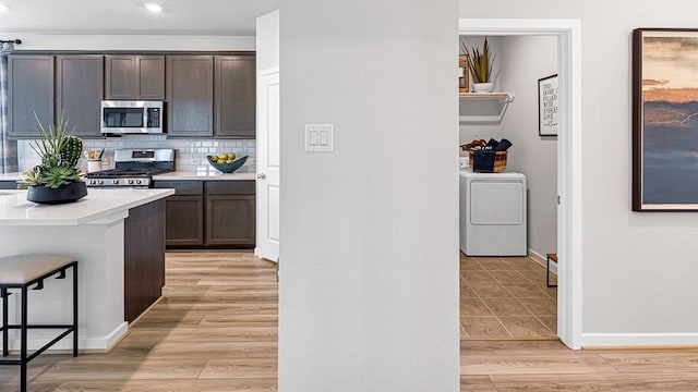 1219 Buffalo Run, Tomball, TX 77375 - kitchen featuring appliances with stainless steel finishes, washer / dryer, light countertops, backsplash, and dark brown cabinetry