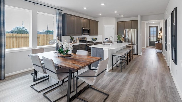 1219 Buffalo Run, Tomball, TX 77375 - kitchen with appliances with stainless steel finishes, dark brown cabinets, a center island with sink, light countertops, and recessed lighting