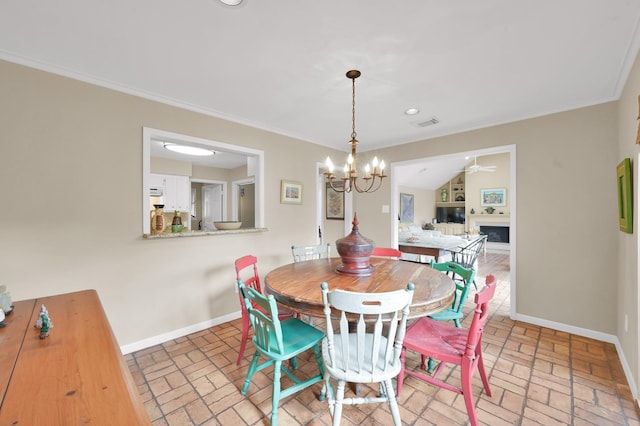 2117 Nantucket Dr, Houston, TX 77057 - dining space featuring brick floors, a chandelier, crown molding, a fireplace, and a ceiling fan