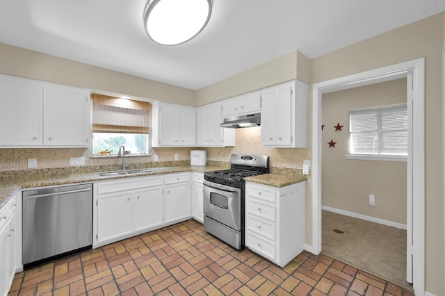 2117 Nantucket Dr, Houston, TX 77057 - kitchen with stainless steel appliances, under cabinet range hood, tasteful backsplash, white cabinetry, and brick patterned floors