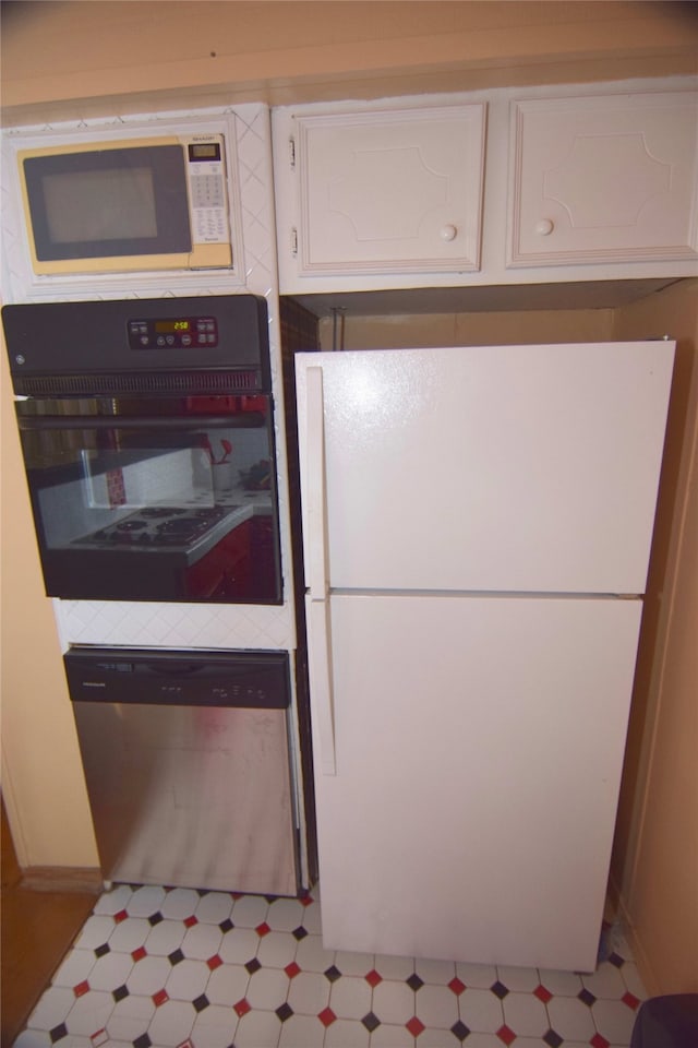 123 Sandpiper Ave, Surfside Beach, TX 77541 - kitchen featuring freestanding refrigerator, black oven, dishwasher, and tile patterned floors