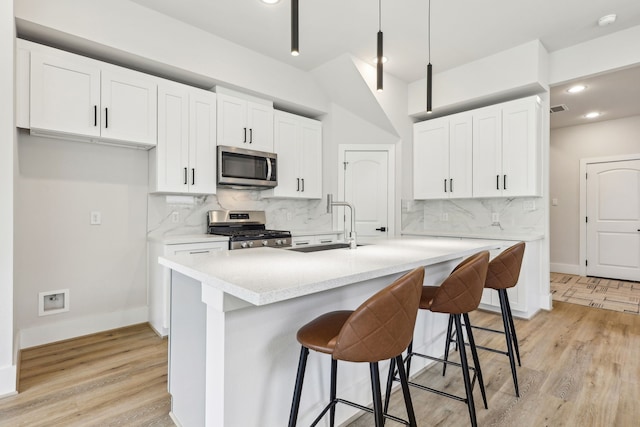 3720 Nathaniel Brown St, Houston, TX 77021 - kitchen featuring stainless steel appliances, decorative backsplash, white cabinets, light countertops, and light wood finished floors